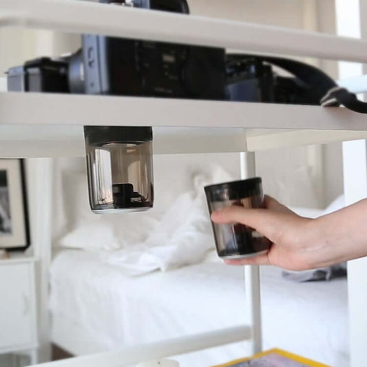 Bluetooth speaker magnetic transparent speaker displayed on a shelf with a camera in the background.