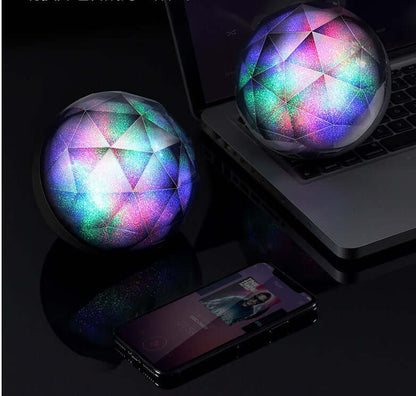 LED seven-color bluetooth speaker magic ball bluetooth speaker beside a laptop and smartphone, showing vibrant colors.