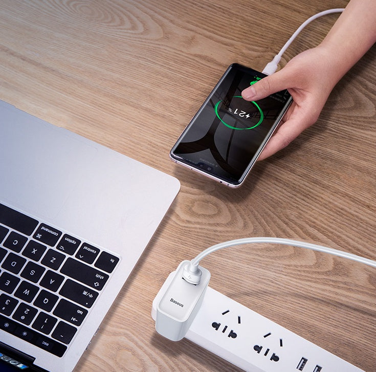 Baseus Android Data Cable Charging Cable connected to a smartphone and laptop on a wooden table.