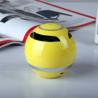 Wireless bluetooth speaker in vibrant yellow color on a table beside a magazine.