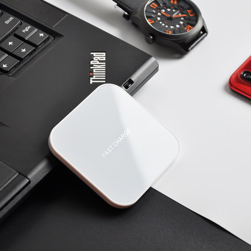 Earphone wireless charger resting on a laptop with a watch beside it, showcasing its sleek design.