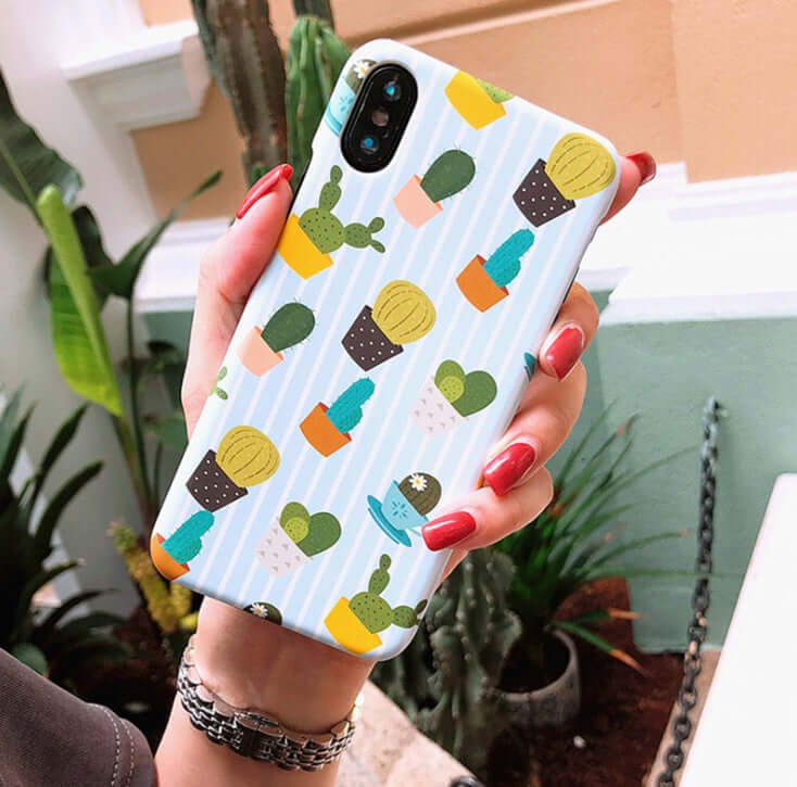 Cactus cartoon iPhone case featuring colorful cactus designs on a light blue background, held in a hand.