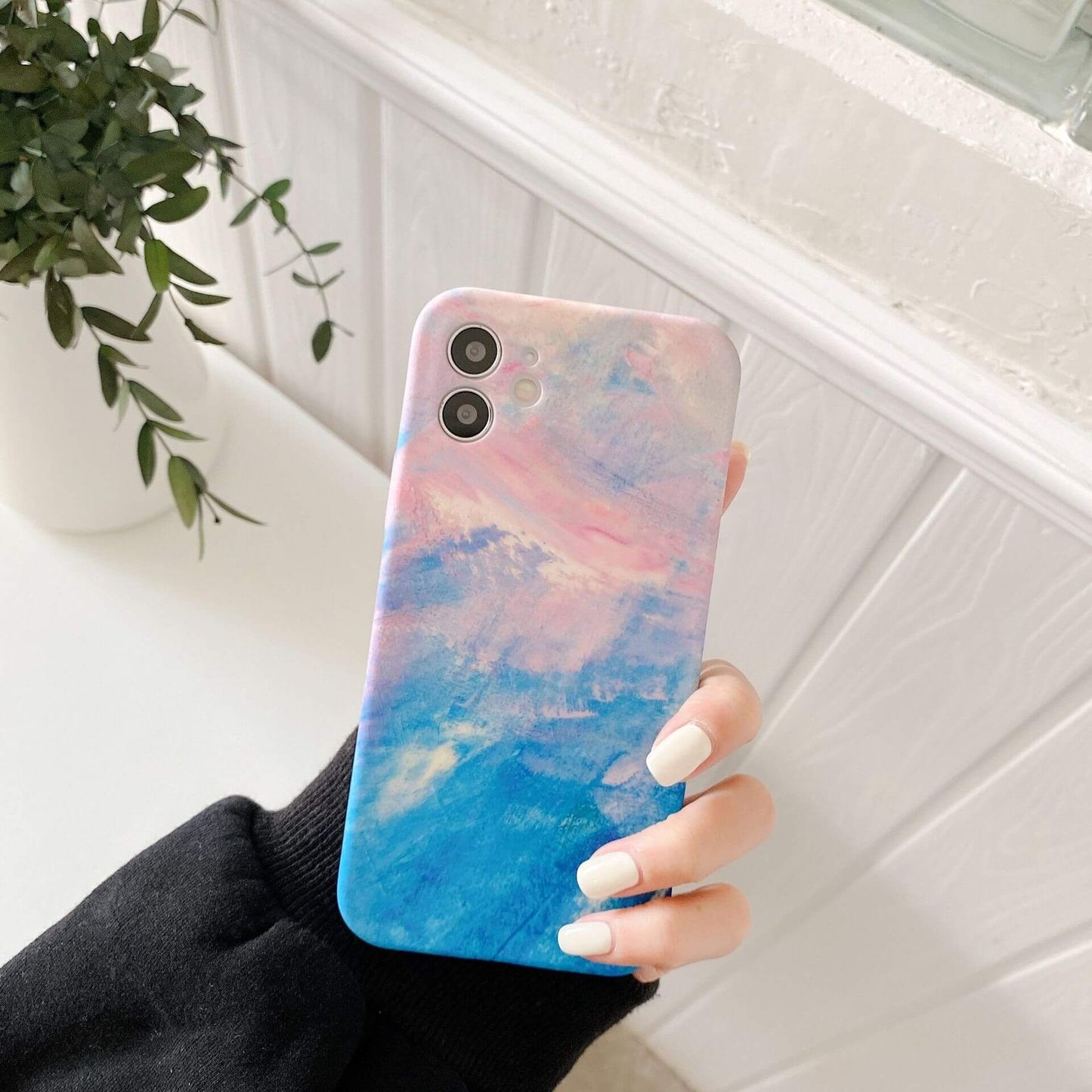 Artistic graffiti phone case featuring a vibrant blue and pink design held by a person.