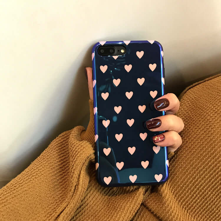 Blu-ray love heart phone case with a dark background and pink heart patterns showcased in a person's hand.