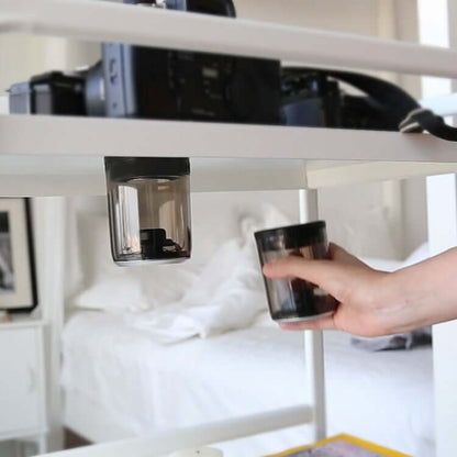 Bluetooth speaker magnetic transparent speaker displayed on a shelf with a camera in the background.